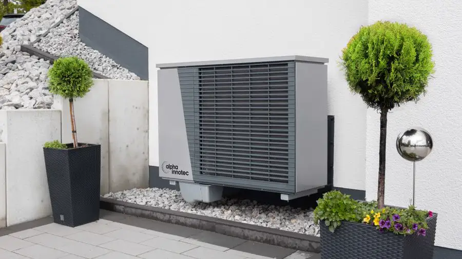 Gray outdoor heat pump unit on a patio beside potted plants