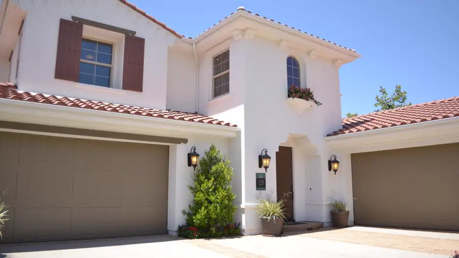 White two-story house with a red tile roof and a two-car garage