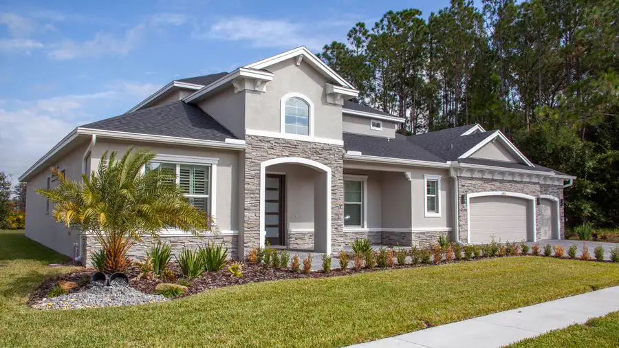 Gray stucco and stone house with a three-car garage and a palm in the front yard