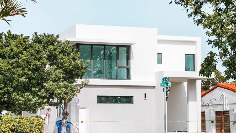 Modern white two-story house with large windows on a street corner
