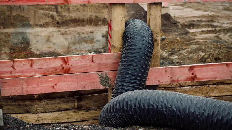 Flexible black duct hose lying on lumber at a job site