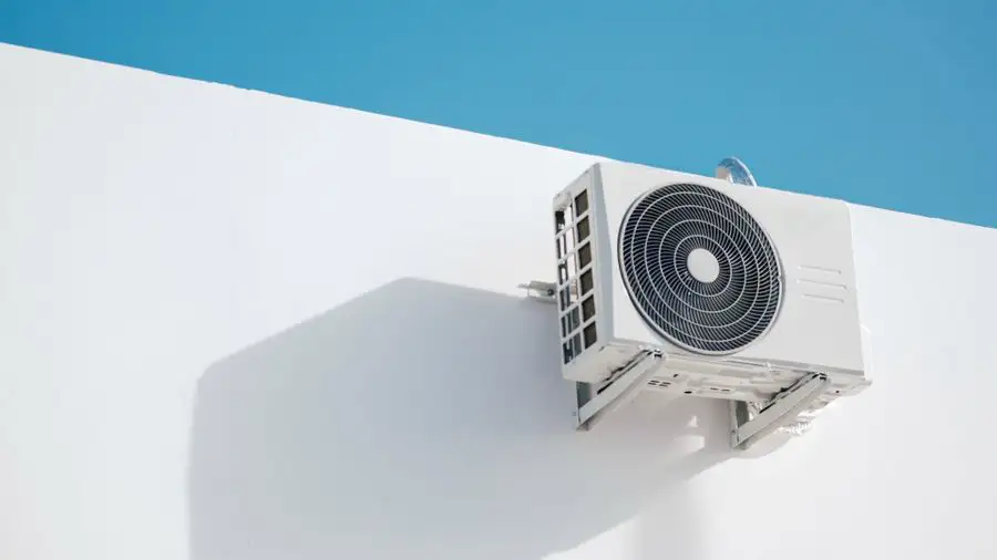 Wall-mounted outdoor air conditioner on a white building against a blue sky
