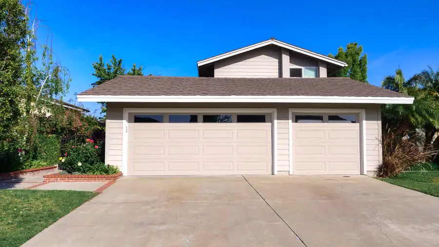 Single-story house with a wide three-car garage and driveway under a blue sky
