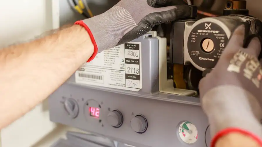 Gloved hands adjusting the pump and controls on a heating unit