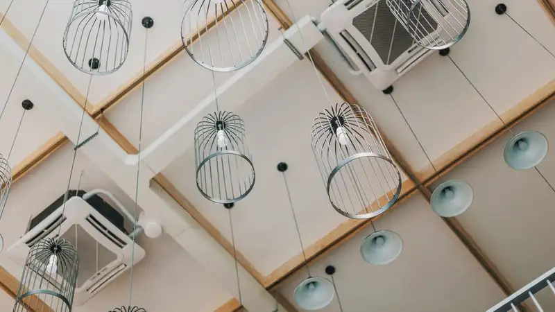 Ceiling with square air-conditioner cassette outlets and hanging wire pendant lamps