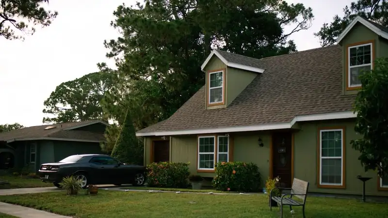 A beautiful suburban home with a well-maintained green lawn and parked car, highlighting residential comfort
