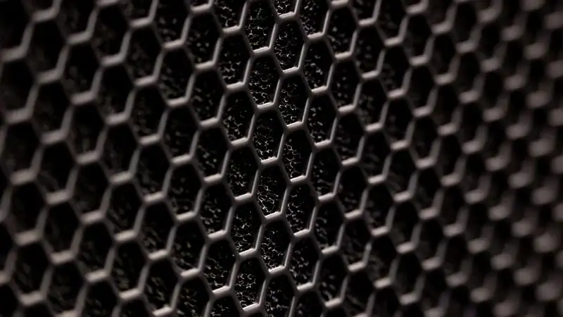 Close-up of a dark metal mesh with a hexagonal pattern, a stand-in for the mesh of an air filter