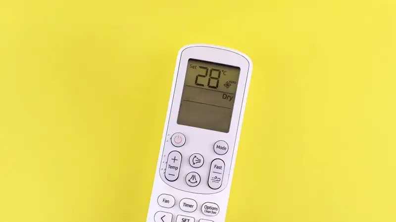 Air conditioner remote with temperature set at 28°C on a yellow background