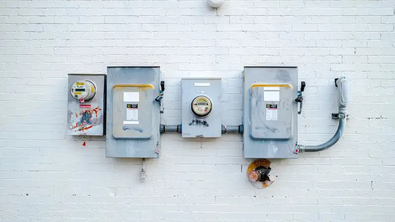 Electrical boxes and power meters mounted on a white brick wall