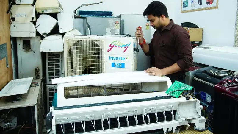 Technician repairing an air conditioner unit in New Delhi workshop