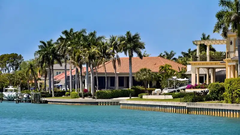 Scenic view of luxury waterfront villas and palm trees under a clear blue sky