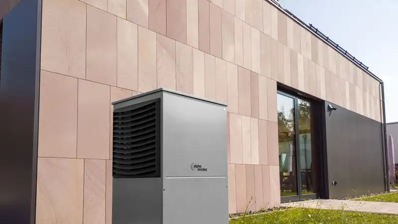 A modern heat pump unit installed outdoors next to a contemporary building, showcasing renewable energy technology