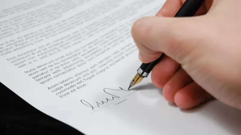 Close-up of a hand signing a legal document with a fountain pen, symbolizing signature and agreement