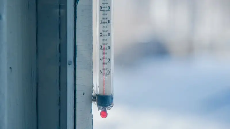 Close-up of an outdoor thermometer against a frosty winter backdrop