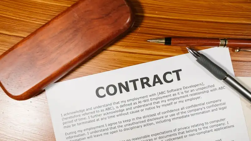 A close-up view of a contract and pen on a wooden desk, ideal for business themes