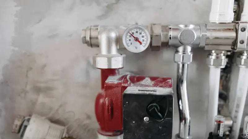 Close-up view of an industrial plumbing system featuring a pressure gauge and steel pipes