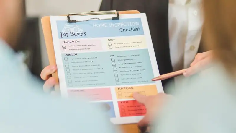 Close-up of hands holding a home inspection checklist clipboard for buyers